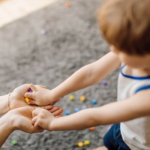 Child handing toys to an adult